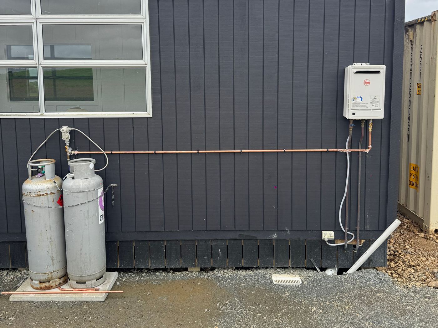 Gas hot water unit and LPG bottles installed on an exterior wall