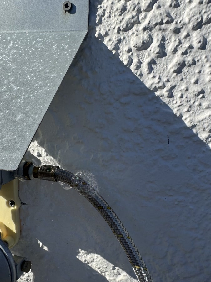 Gas regulator and braided connection hose fitted on an exterior wall by Fernz Gas & Plumbing Specialist
